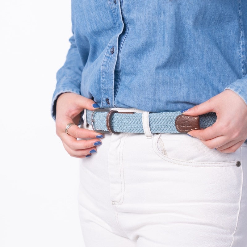 Person wearing a denim shirt and white pants with a belt.