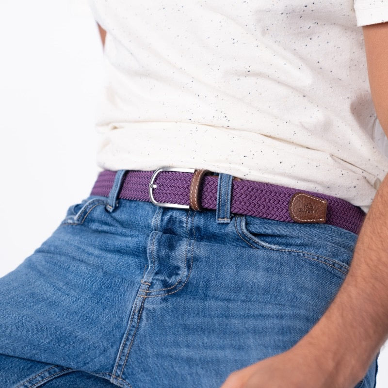 Person wearing a plum belt with a white shirt and blue jeans on a white background